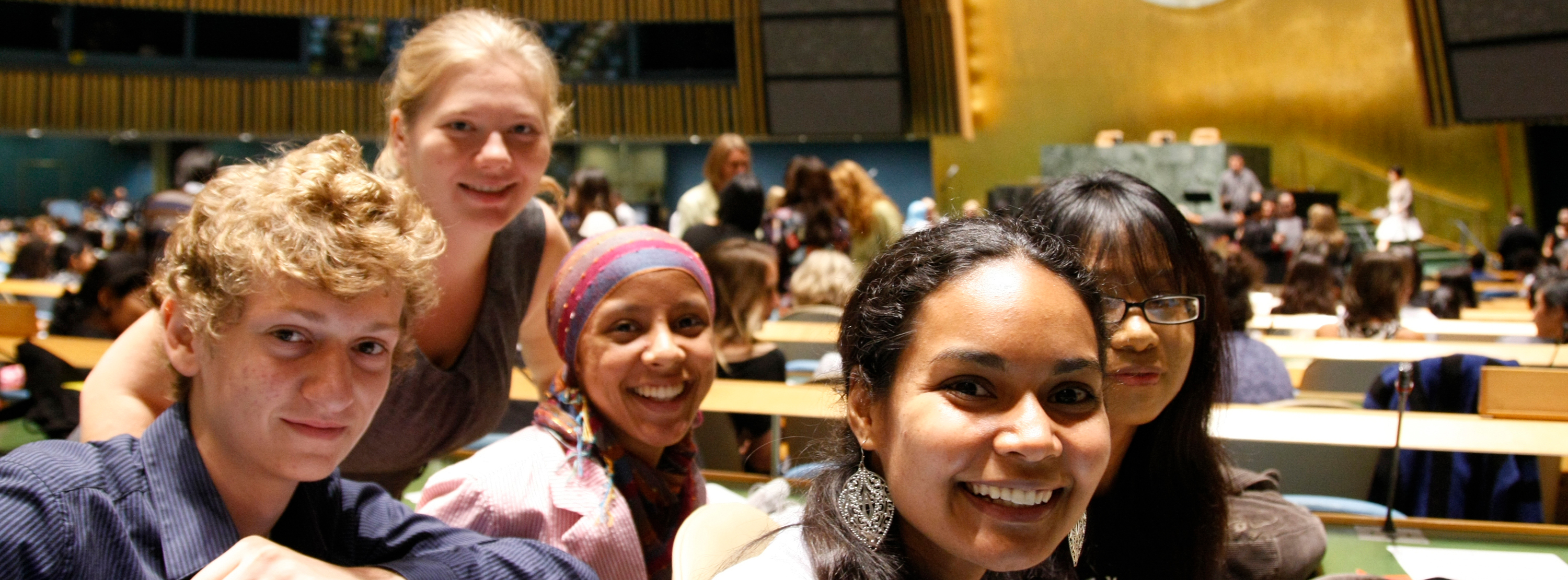 联合国大会堂内，一群笑容满面的青年人。