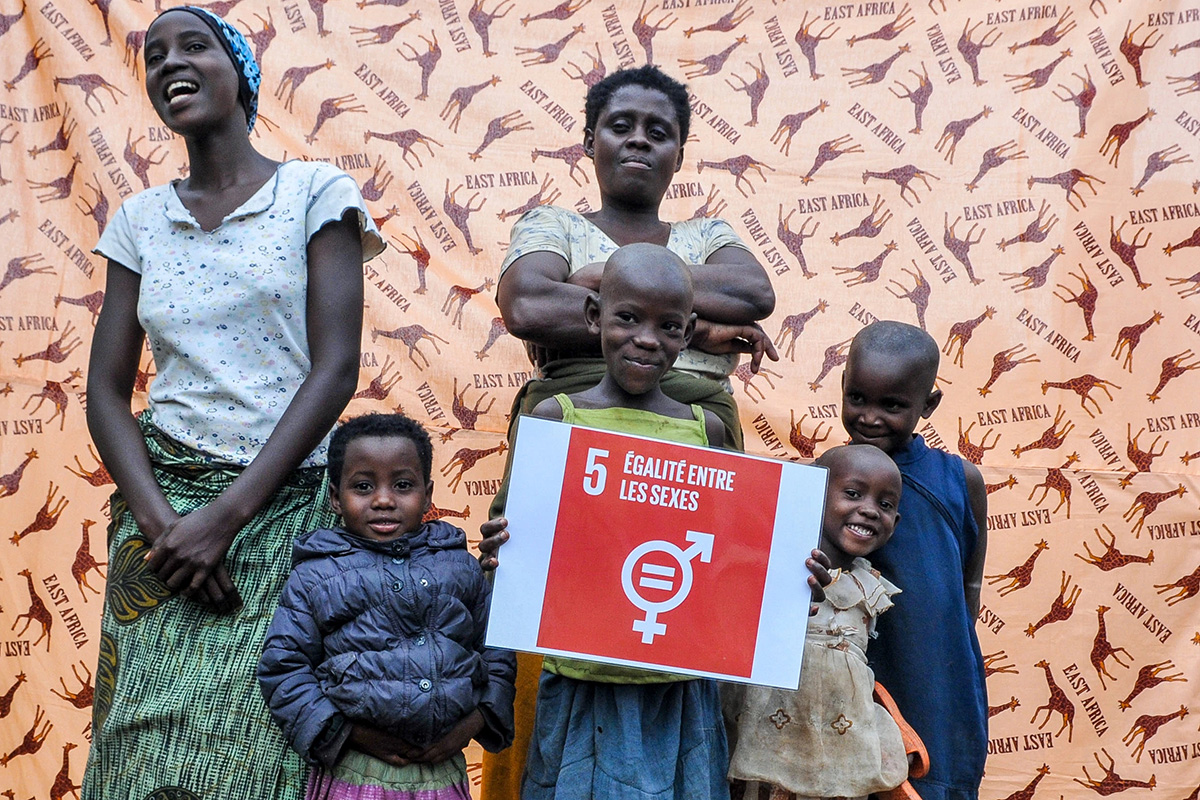 Kids and their mom pose with a SDG 5 sign that reads “Gender equality”.