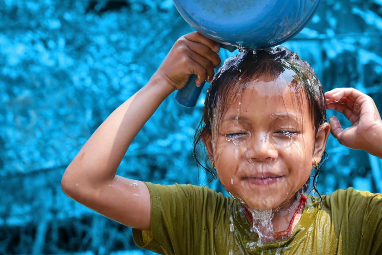 La cara de satisfacción de una niña al refrescarte vertiéndose un cacito de agua en la cabeza.  