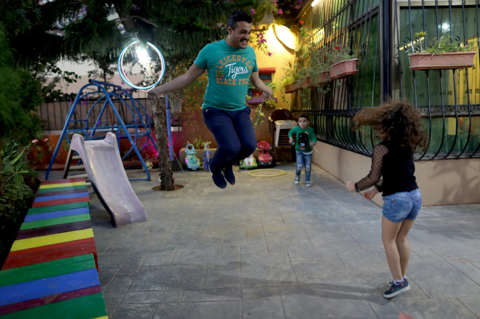 father jumping while playing with his kids in the yard