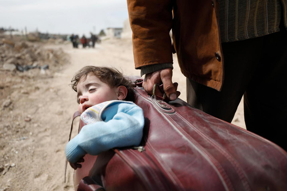 a child sleeps while being carried in a suitcase