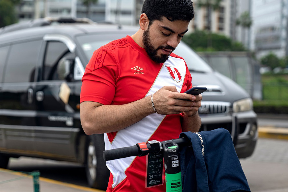A consumer uses his mobile phone to unlock a scooter sharing rental service in Lima, Peru