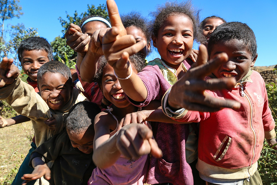 A group of happy children smiling and pointing at the camera. 